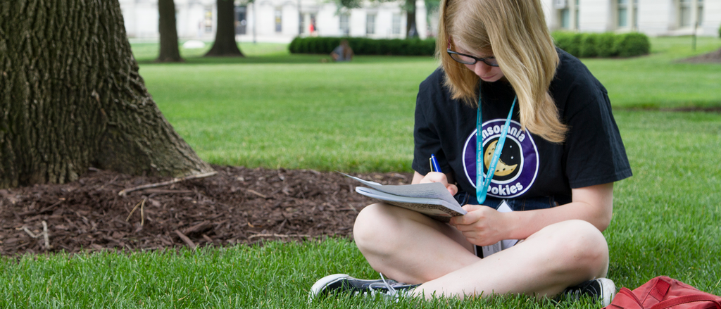 online high school creative writing courses student sitting in grass writing in notebook