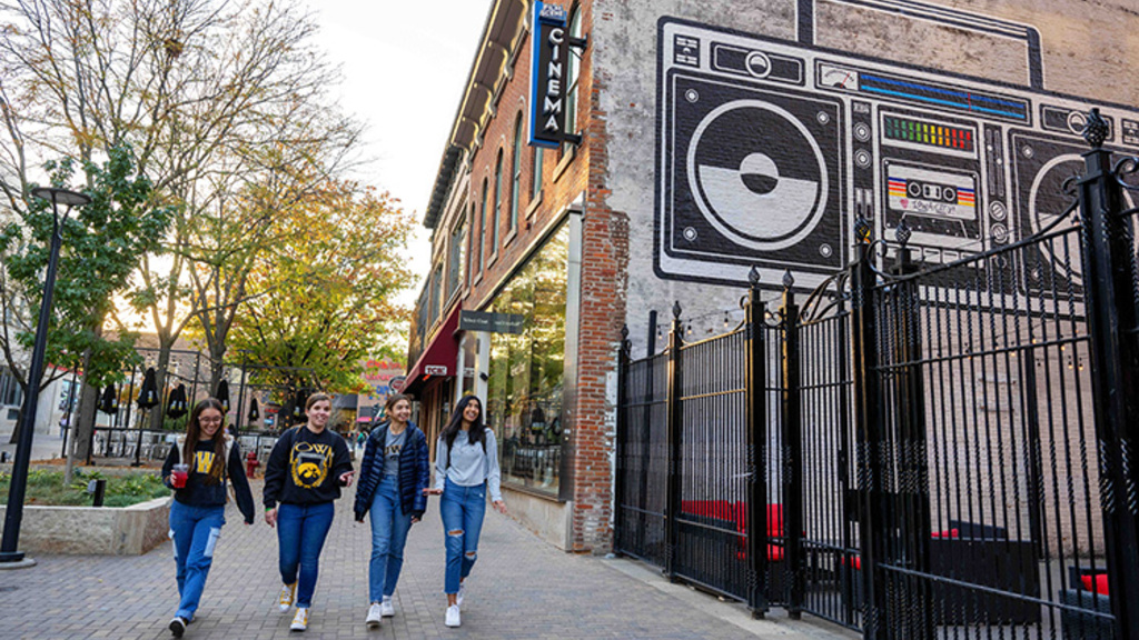 Downtown Iowa City with group walking near buildings and wall mural of old-school boombox